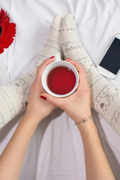 Mujer tomando una taza de té en la cama —  Fotos de Stock