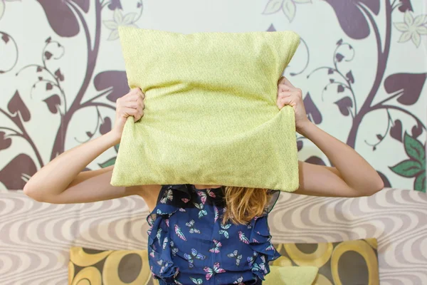 Девушка прячется за подушкой — стоковое фото