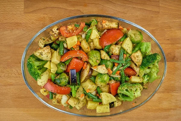 Vegetable stew in a transparent plate. Juicy vegetable stew in spices, top view. Vegetarian food, vegetable mix.