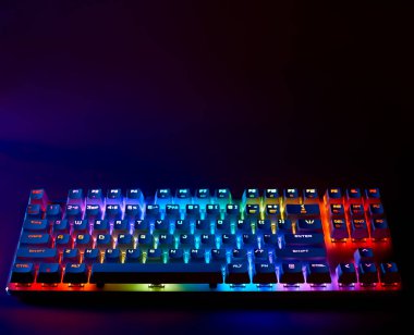 Gökkuşağı klavyesi. RGB ışığıyla klavye çalıyorum. Karanlık bir odada arka planda klavye, boşluğu kopyala.