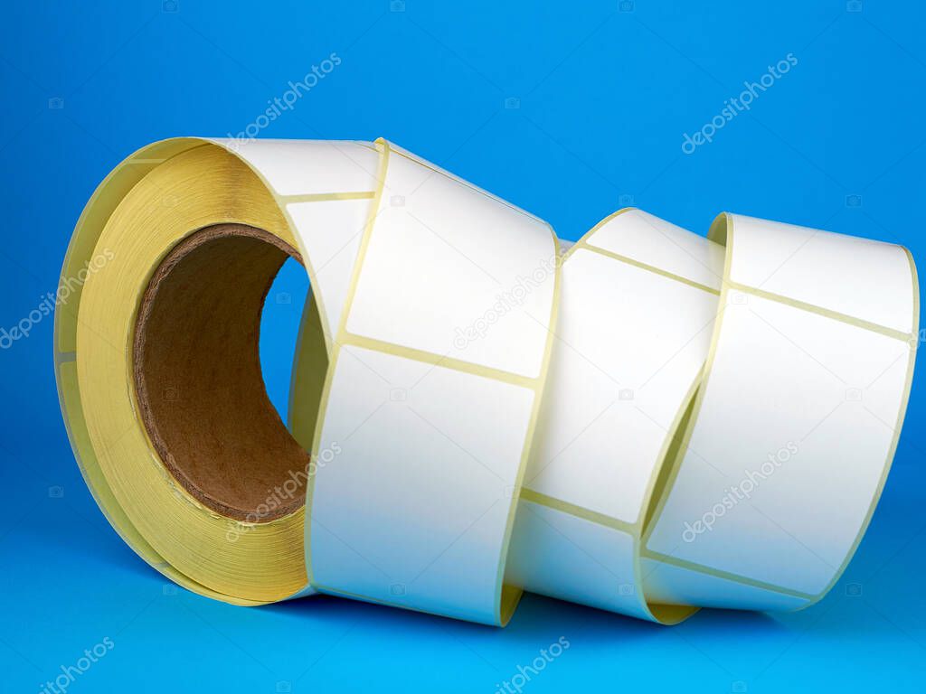 White roll of labels for thermal perforation on a blue background. Babina of self-adhesive stickers. Self-adhesive white label roller for printing or manufacturing