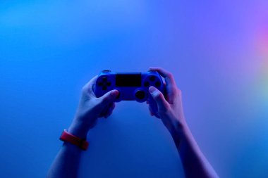 Karanlık bir odada oyun kumandasını tutan birinin elleri. Oyun konsepti. Video oyunu konsolu oynayan adam, neon ışığı.