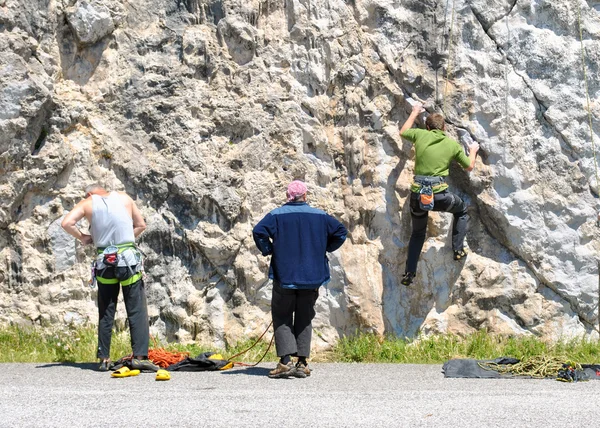 Three people climbing up a rock face — Stock Photo, Image