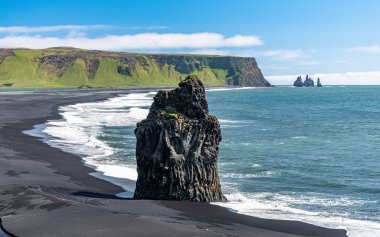 Arnardrangur, Güney İzlanda 'da Vik yakınlarında Reynisfjara Sahili' nin kara kumları üzerinde duran bir bazalt deniz yığını. Arka planda Reynisdrangar deniz yığınları var.