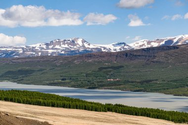 Lagarfljot Gölü, Hallormsstadur Ulusal Ormanı ve İzlanda 'nın güneydoğusundaki dağların panoramik manzarası güneşli bir öğleden sonra