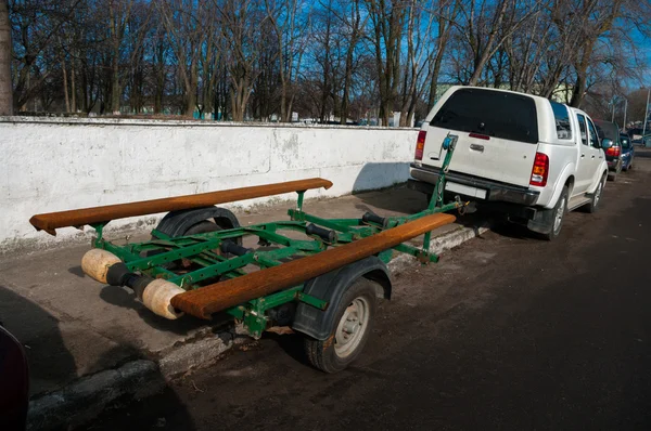 Auto met groene aanhangwagen voor het vervoer van de boot op de parkeerplaats — Stockfoto