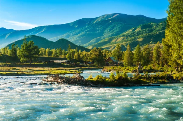 Blue wide river flowing in front of the house in the mountains — Stock Photo, Image