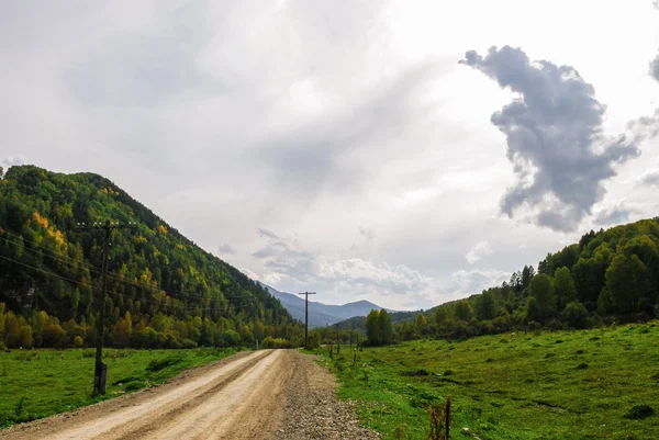 Dirt road passing among the forested hills — Stock Photo, Image