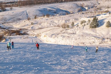 Kayak ve snowboard karla kaplı tepenin eteklerinde insanlar