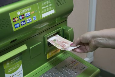 Bir adam (kadın) bir banknot Sberbank Atm bir yuva koyar..