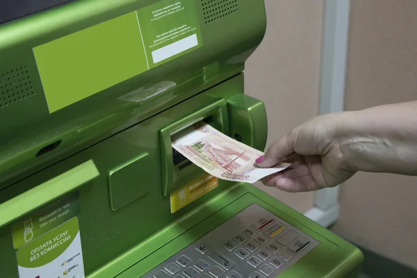 A man (woman) puts a banknotes into a slot of the ATM. — Stock Photo, Image