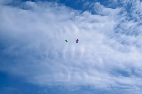 Tres globos multicolores vuelan en el cielo azul con nubes —  Fotos de Stock