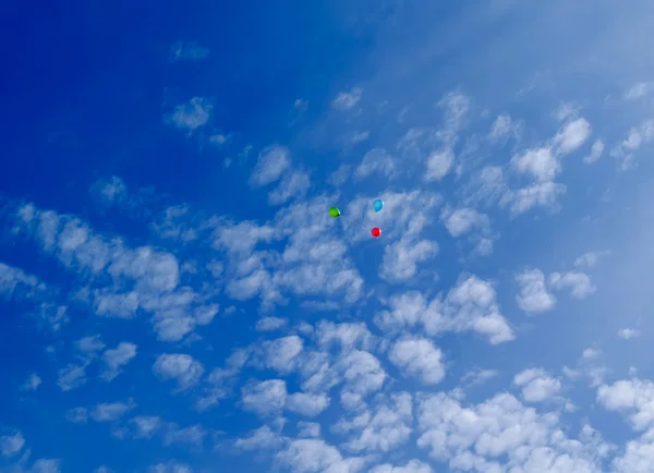 Tres globos multicolores vuelan en el cielo azul con nubes —  Fotos de Stock