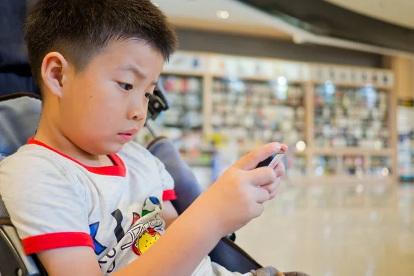 Asyalı Çinli çocuk akıllı telefon oynuyor, çocuk telefon kullanıyor ve oyun oynuyor, bağımlı oyun ve çizgi film oynuyor.
