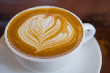 Sıcak latte sanat kahvesi, ahşap masada, dinlenme zamanı.