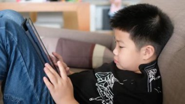 Asyalı Çinli çocuk akıllı telefon oynuyor, çocuk telefon kullanıyor ve oyun oynuyor, bağımlı oyun ve çizgi film oynuyor.