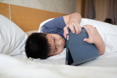 Asyalı Çinli çocuk akıllı telefon oynuyor, çocuk telefon kullanıyor ve oyun oynuyor, bağımlı oyun ve çizgi film oynuyor.