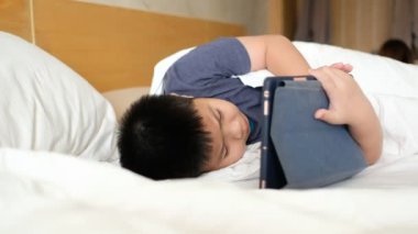 Asyalı Çinli çocuk akıllı telefon oynuyor, çocuk telefon kullanıyor ve oyun oynuyor, bağımlı oyun ve çizgi film oynuyor.