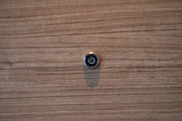 closeup eye door on wood background, peephole
