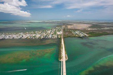 Florida Keys. Key West, Florida. Tropikal mavi su boyunca uzanan uzun bir otoyolun havadan görünüşü, manzaralı kıyı manzarası, botlar, köprüler ve yaz yolculuğu titreşimleriyle adaları birbirine bağlıyor. ABD turizm tatili