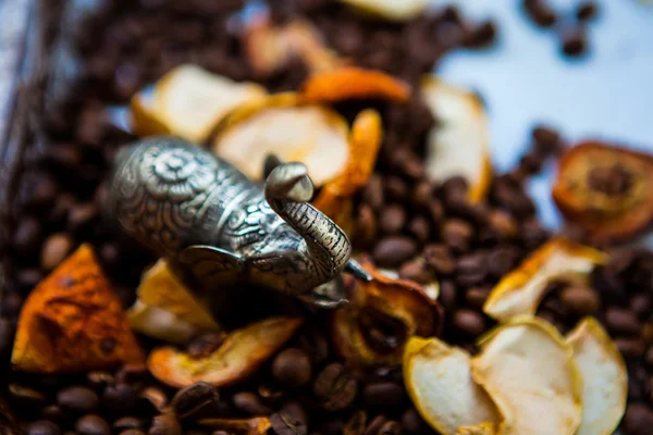 Small metal statuette of elephant, coffee beans and dried apples — Stock Photo, Image