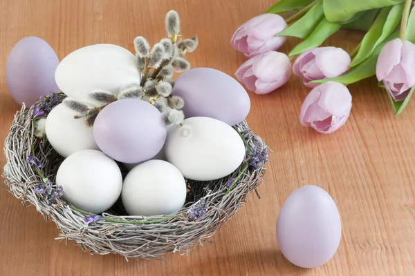Fialová a bílá vejce v hnízdě. Velikonoční dekorace — Stock fotografie