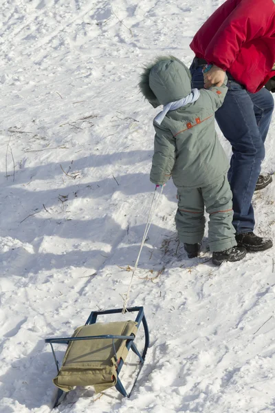 父亲扶着儿子用雪橇爬山. — 图库照片