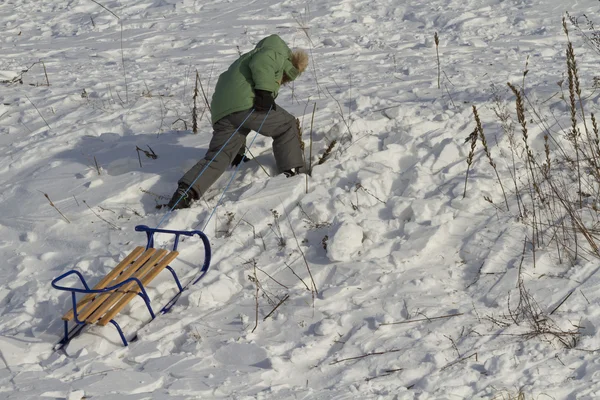 有雪橇的男孩有困难地锻造前进. — 图库照片