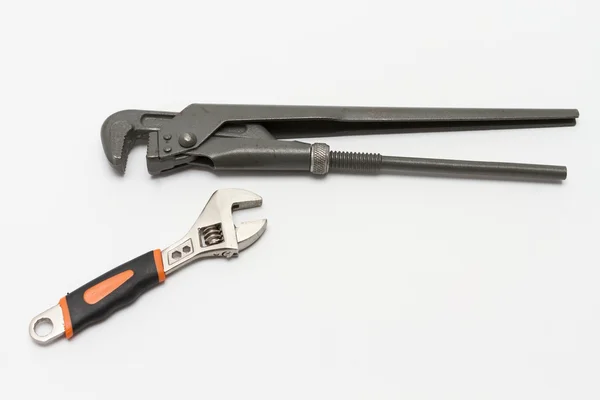 Pipe wrench and a small adjustable wrench on a white background close-up. — Stock Photo, Image