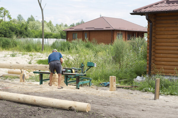 Плотник пилит бревна на машине
.