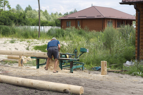 Плотник пилит бревна на машине
.