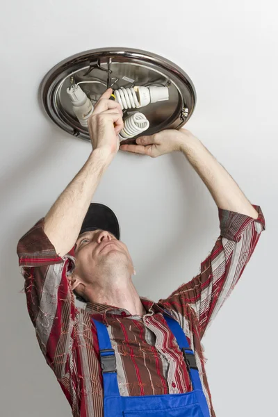 Elektrikář nainstaluje rozsvícení světla na stropě místnosti. — Stock fotografie
