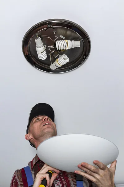 Electrician installs lighting the lamp on the ceiling of the room. — Stock Photo, Image