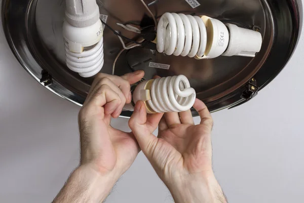 Os eletricistas são parafusados na lâmpada de teto do cartucho lâmpadas economizadoras de energia . — Fotografia de Stock