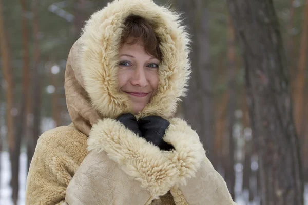 Mädchen mit einem Lächeln umhüllt von der Kälte in warmem Schaffell. — Stockfoto