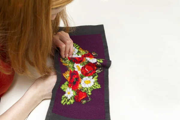 Woman embroiders bead pattern of flowers poppies and daisies. — Stock Photo, Image