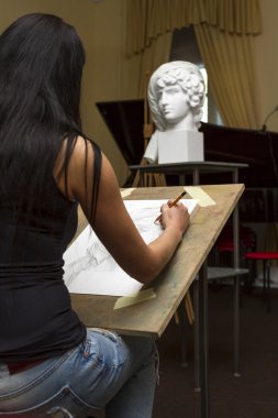 Genç sanatçı bir kalem portresi boyalar.