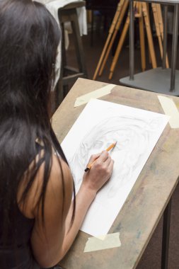 Genç sanatçı bir kalem portresi boyalar.