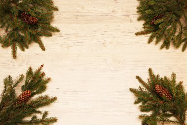 Noel ve Yeni Yıl geçmişi. Kozalaklı dallar, Noel kurabiyeleri ve Noel toplarıyla süslenmiş ahşap bir arka planda yatıyor..