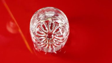 Portakal suyu kırmızı zemin üzerinde şeffaf bir cam bardağa dökülür. Yazın susuzluğunu gider..