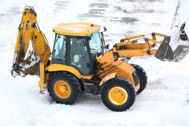 Traktör kışın karı kaldırır. Bir traktör kışın araba için yolu temizler. Kış aylarında yayaların önünü temizler..