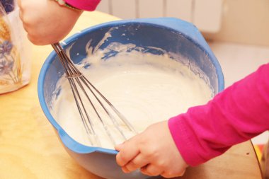Küçük kız turta pişirmek için hamur hazırlamaya yardım eder. Kız annesinin yemek yapmasına yardım ediyor..