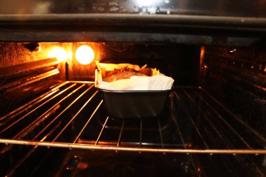 Baked cakes - muffins in the oven on a steel grill on a black background, close-up. The concept of the process of baking and cooking breakfast.