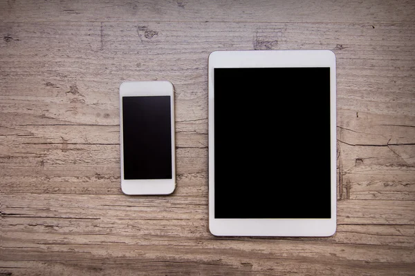 smartphone and a tablet on the wooden background 