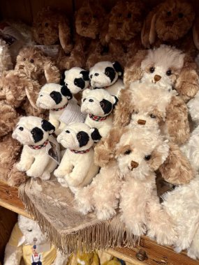 Oyuncak bir butiğin ahşap rafında şirin pelüş köpek ve buldog koleksiyonu..