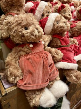 Kırmızı Noel kıyafetleri ve ahşap bir rafta Noel Baba şapkaları giyen şirin pelüş ayıların yakın çekimi..