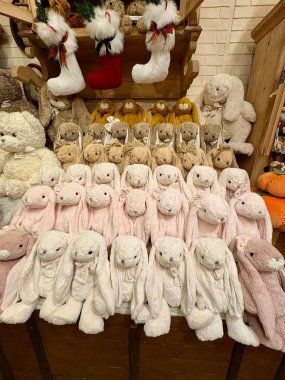 Noel için ahşap bir rafta pastel renkli şirin pelüş tavşan oyuncakları sergileniyor..