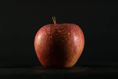 Siyah arkaplanda kırmızı elma ve üzerinde su damlacıkları