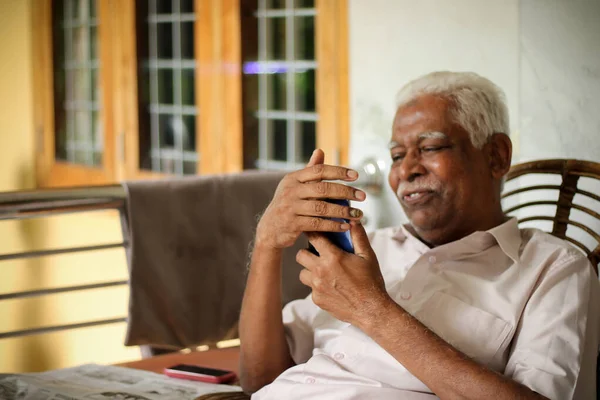 Senior citizen enjoying social media in mobile phone at home