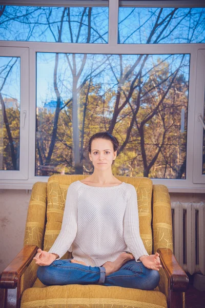 The girl in a white blouse sits on a yellow chair